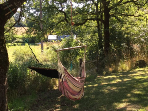 Sedia amaca e amaca appese tra gli alberi al suggestivo campeggio Mas du Midi in Occitanie, Francia.