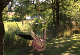 Sedia amaca e amaca appese tra gli alberi al suggestivo campeggio Mas du Midi in Occitanie, Francia.