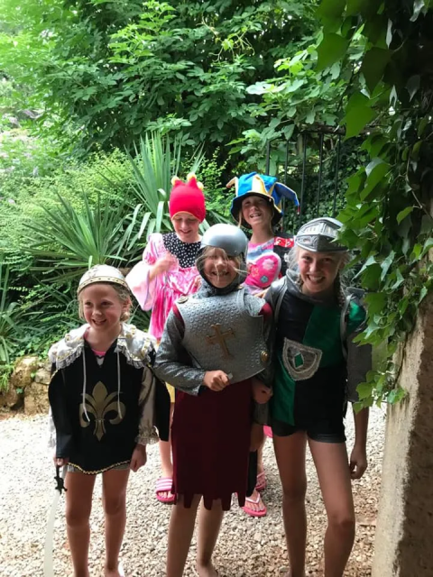 Bambini in costumi medievali colorati giocano insieme al campeggio Mas du Midi in Occitania, Francia.