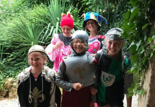 Bambini in costumi medievali colorati giocano insieme al campeggio Mas du Midi in Occitania, Francia.