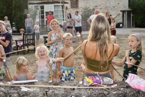Bambini e adulti si divertono insieme all'aperto in un campeggio villaggio vacanze in Occitania, Francia.