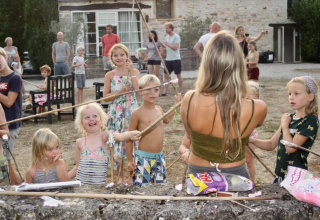 Bambini e adulti si divertono insieme all'aperto in un campeggio villaggio vacanze in Occitania, Francia.