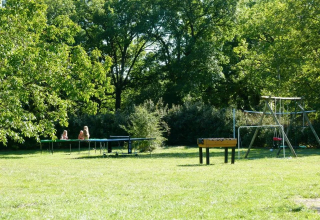 Area giochi all’aperto al campeggio Mas du Midi in Occitania, Francia, con calcetto e altalene verdi.