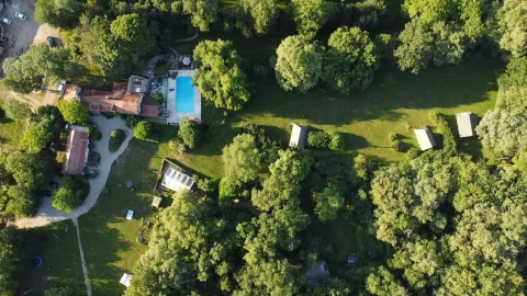 Vista aerea del campeggio Mas du Midi in Occitania, Francia, con piscina e molto verde intorno.