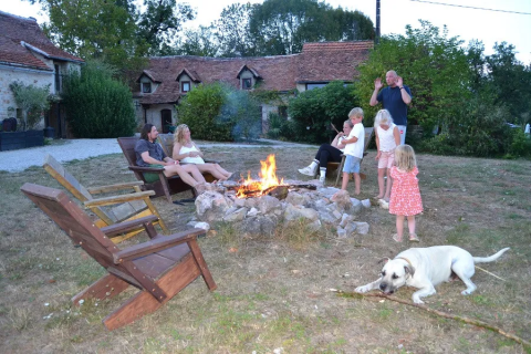 Famiglia che si gode un falò al campeggio Mas du Midi in Occitania, Francia, con bambini, adulti e cane.