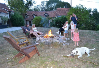 Famiglia che si gode un falò al campeggio Mas du Midi in Occitania, Francia, con bambini, adulti e cane.