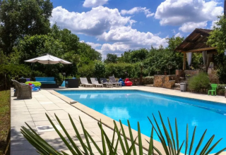 Swimming pool with loungers, umbrellas, and greenery at Campsite Mas du Midi, Occitanie, France.