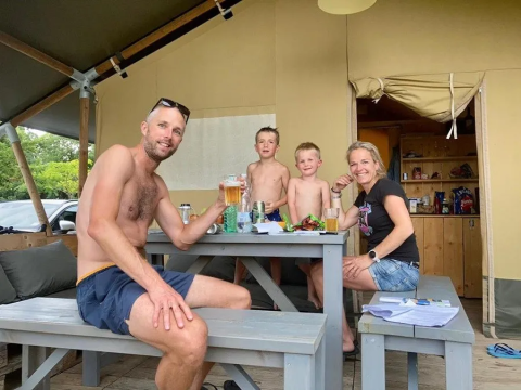 Familie nyder en afslappet dag udenfor en safaritelt på Campingplads Mas du Midi i Frankrig med mad og drikke.