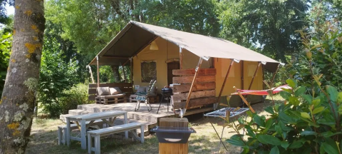 Safaritelt ved Campsite Mas du Midi i Frankrig, med udendørs siddeplads, borde og grill omringet af natur.