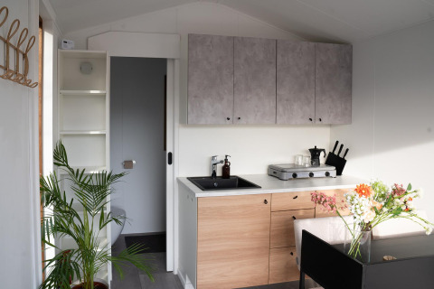 Pequeña cocina y área de comedor con plantas y flores en Slowcabin Nest, Zomerlicht, Países Bajos.