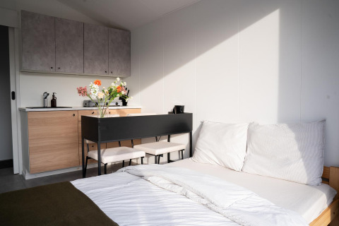 Interior moderno y luminoso en Slowcabin Nest de Zomerlicht, Países Bajos, con cama y cocina pequeña.