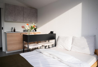 Intérieur moderne et lumineux au Slowcabin Nest à Zomerlicht, Pays-Bas, avec lit et petite cuisine.
