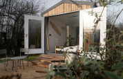 Vue extérieure de la cabane Slowcabin Nest à Zomerlicht aux Pays-Bas avec portes ouvertes et terrasse.