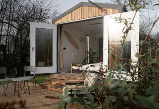 Vista exterior de la cabaña Slowcabin Nest en Zomerlicht, Países Bajos, con puertas abiertas y terraza.