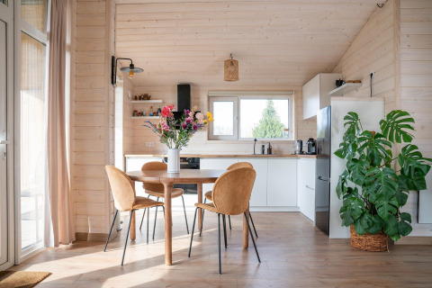Lichte, moderne keuken en eetruimte met houten wanden, grote plant en bloemen bij Slowlodge, Zomerlicht, Nederland.