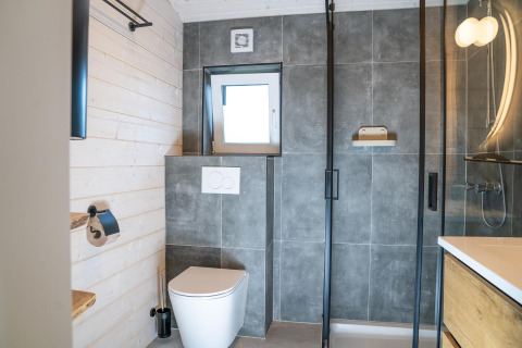 Moderne badkamer met grijze tegels, douche en toilet in Slowlodge bij Zomerlicht, Nederland.