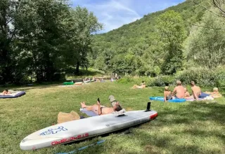 Villeggianti sdraiati sull’erba al campeggio La Prade in Occitania, Francia, immersi nella natura verde.