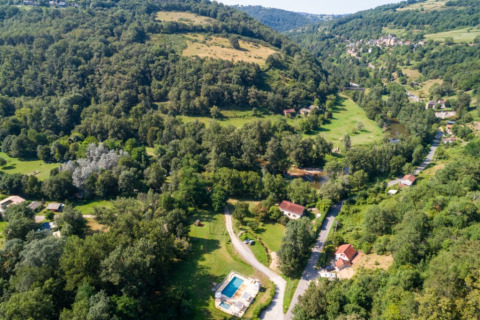 Vista aerea del campeggio La Prade in Occitania, Francia, circondato da colline verdi e una piscina.