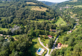 Vista aerea del campeggio La Prade in Occitania, Francia, circondato da colline verdi e una piscina.