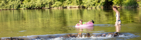 Donna e bambino si divertono nel fiume al campeggio La Prade in Occitania, Francia, immersi nella natura.