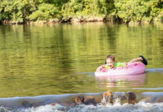 Donna e bambino si divertono nel fiume al campeggio La Prade in Occitania, Francia, immersi nella natura.