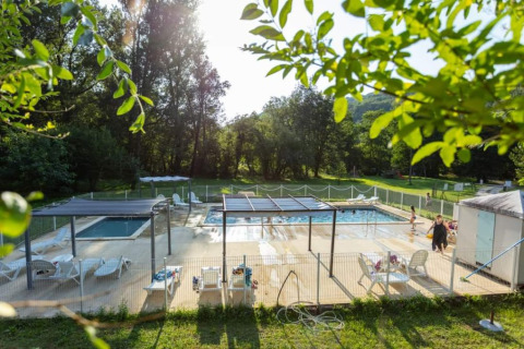 Area piscina all'aperto al campeggio La Prade in Occitania, Francia, immersa nel verde.