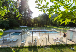 Area piscina all'aperto al campeggio La Prade in Occitania, Francia, immersa nel verde.
