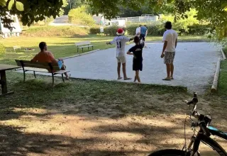 Persone giocano all'aperto al campeggio La Prade in Occitania, Francia, con una bici in primo piano.