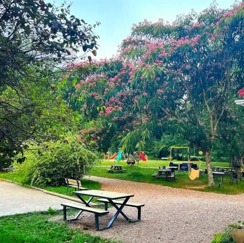 Aree picnic, alberi fioriti e parco giochi per bambini al campeggio La Prade, Occitania, Francia.