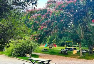 Aree picnic, alberi fioriti e parco giochi per bambini al campeggio La Prade, Occitania, Francia.