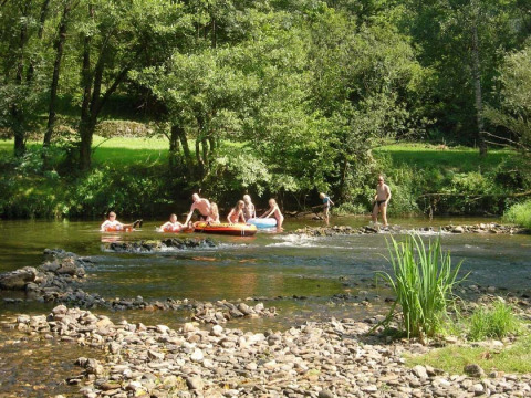Persone si divertono in un fiume poco profondo vicino al campeggio La Prade in Occitania, Francia, circondate dal verde.