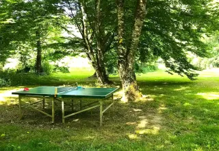 Tavolo da ping pong all'aperto tra gli alberi al campeggio La Prade, Occitania, Francia, giornata di sole.
