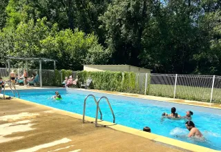 Gezinnen zwemmen en ontspannen bij het buitenzwembad op Camping La Prade in Occitanië, Frankrijk.