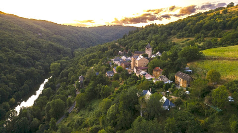 Vista aerea di un villaggio nella valle circondato da verde e sistemazioni glamping in un parco vacanze.