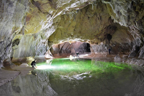 Esploratori osservano un lago sotterraneo verde brillante in una grotta vicino a Montirat, Occitania, Francia.