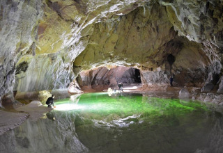 Esploratori osservano un lago sotterraneo verde brillante in una grotta vicino a Montirat, Occitania, Francia.