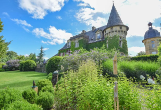 El Domaine d'Essendieras en Nouvelle-Aquitaine, Francia, muestra un castillo rodeado de jardines verdes y cielo azul.