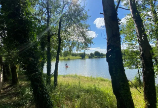 Vista soleada entre árboles de un lago cerca de Saint-Médard-d'Excideuil, Nouvelle-Aquitaine, Francia.