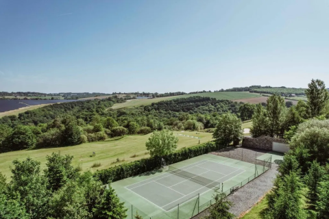 Campo da tennis immerso nel verde tra colline al Domaine d’Essendieras, Nouvelle-Aquitaine, Francia.