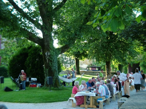 Buitengebeuren nabij Saint-Médard-d'Excideuil, Frankrijk, mensen eten onder bomen met live muziek.