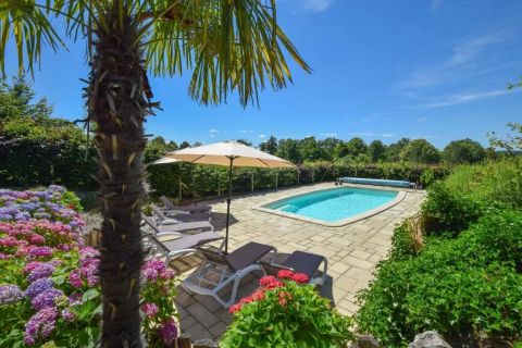 Zona de piscina soleada con tumbonas, sombrilla, palmera y flores en Domaine d'Essendieras, Nouvelle-Aquitania.