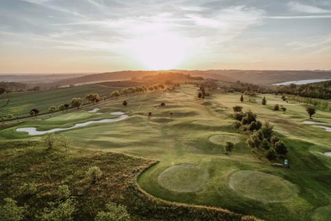 Zonsondergang op de golfbaan van Domaine d'Essendieras in Nouvelle-Aquitaine, Frankrijk, omringd door groen.