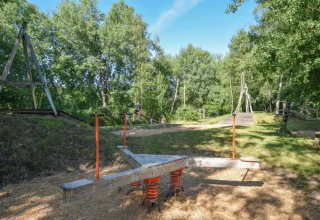 Udendørs legeplads i Domaine d' Essendieras, Nouvelle-Aquitaine, Frankrig, omgivet af træer og natur.