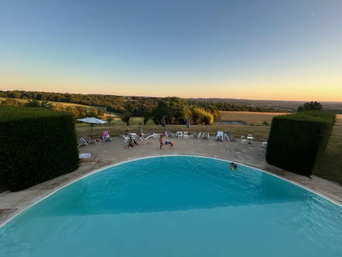Blick auf Pool, Liegestühle und Landschaft im Domaine d'Essendieras, Nouvelle-Aquitaine, Frankreich, bei Sonnenuntergang.