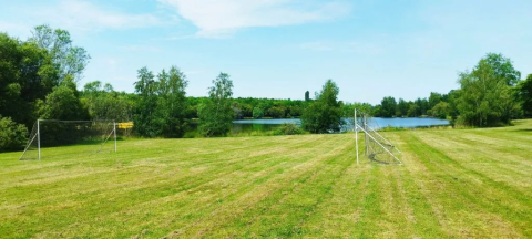 Fußballfeld mit Toren auf einer Wiese nahe einem See, umgeben von Bäumen im Domaine d'Essendieras, Frankreich.