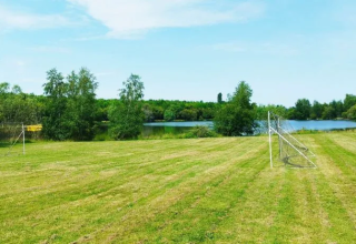 Soccer field with goals on grass near a lake, surrounded by trees at Domaine d'Essendieras, Nouvelle-Aquitaine.