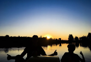 Siluetas de dos personas en la orilla de un lago al atardecer cerca de Saint-Médard-d'Excideuil, Nueva Aquitania, Francia.
