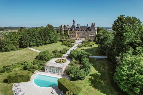 Aerial view of Domaine d' Essendieras holiday park in Nouvelle-Aquitaine, France, featuring a castle and pool.