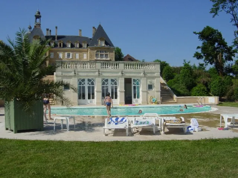 Piscina con lettini e persone davanti a un castello al Domaine d'Essendieras, Nouvelle-Aquitaine, Francia.