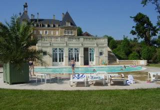 Piscine avec transats devant un château au Domaine d'Essendieras en Nouvelle-Aquitaine, France.